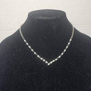 Elegant V-shaped tennis necklace features a sophisticated bezel-set design